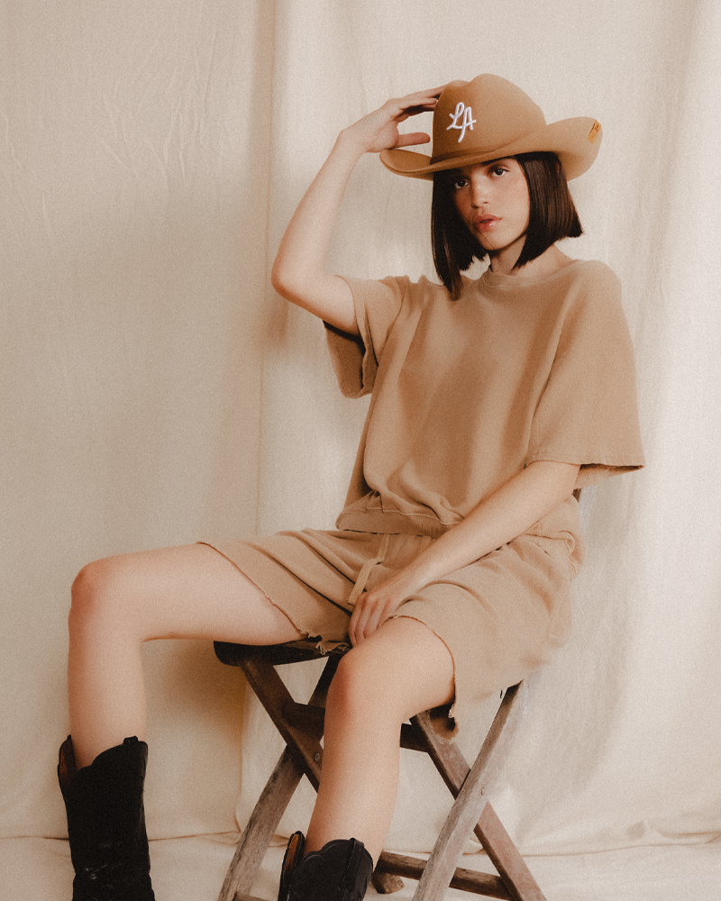 Model wearing a 100% wool Teddy Headwear Cowboy Hat in traditional Western cowboy hat silhouette for unisex in premium cream or brown wool colors with vintage fashion photoshoot aesthetic.