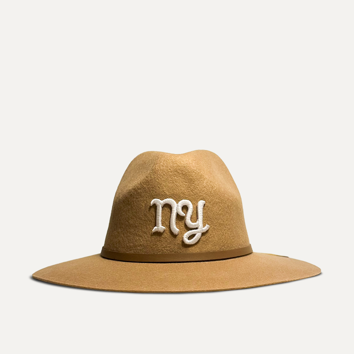 Teddy Headwear New York Monogram Fedora, unisex wool fedora with wide brim, leather band, and embroidered T logo, available in cream and brown. 