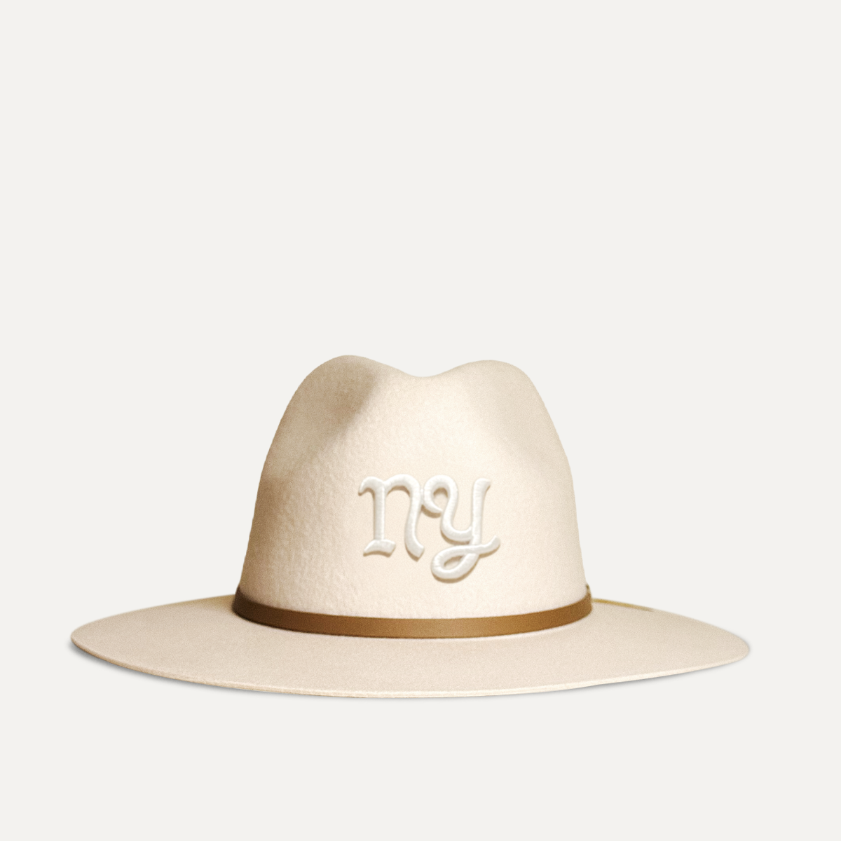 Teddy Headwear NY Monogram Fedora, unisex wool fedora with wide brim, leather band, and embroidered T logo, available in cream and brown. 