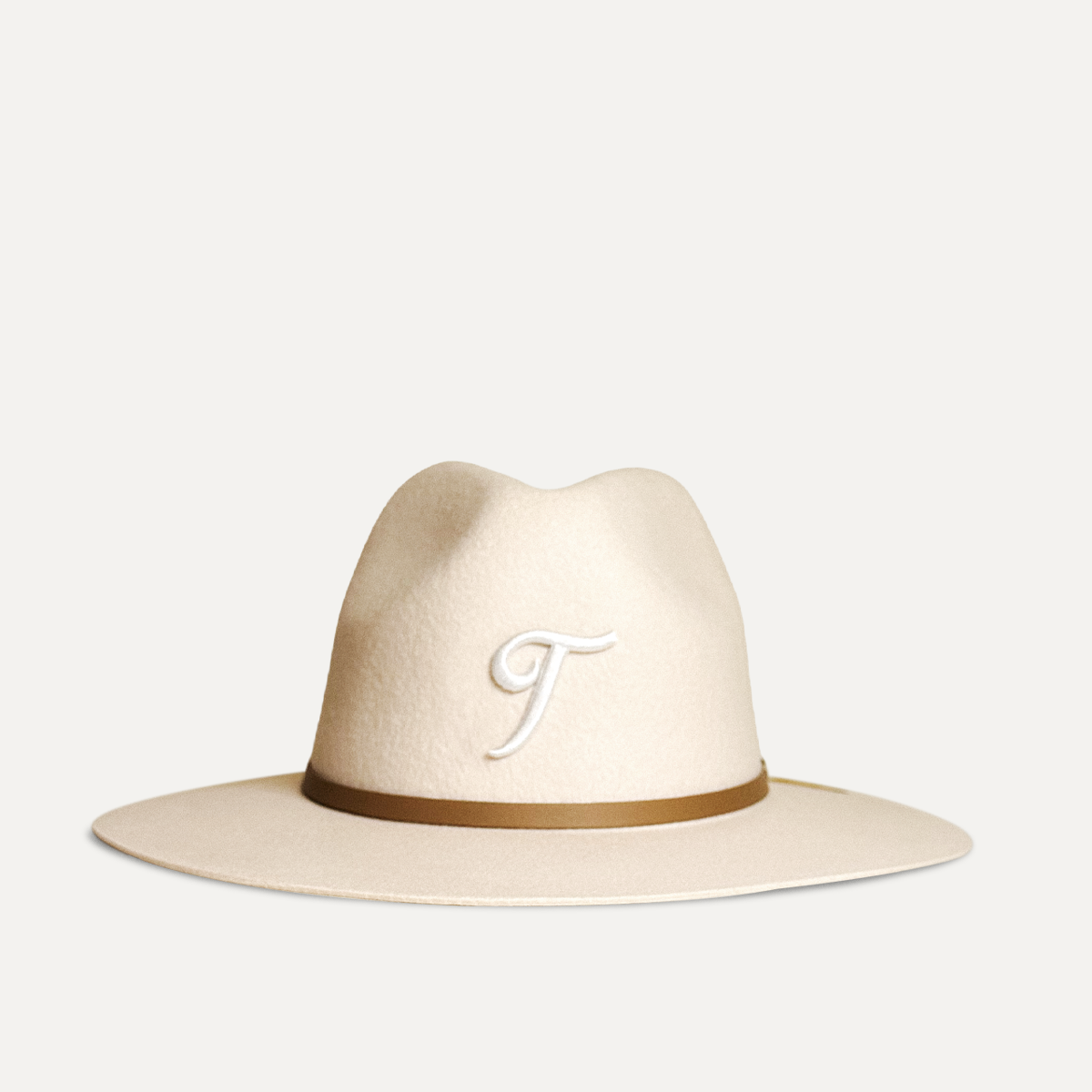 Teddy Headwear Texas Monogram Fedora, unisex wool fedora with wide brim, leather band, and embroidered T logo, available in cream and brown, designed in America.